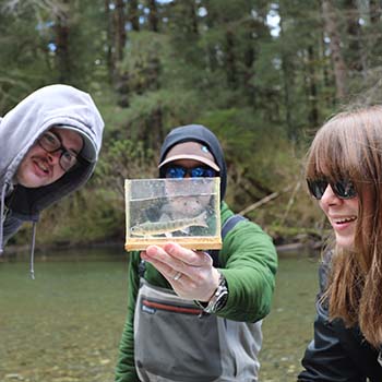 A group of students holds out some beautiful farmed oysters while visiting Hump Island Oyster Company offshore from Ketchikan.